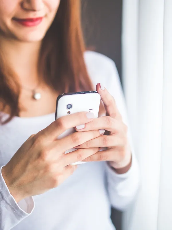 スマホを手に微笑む女性