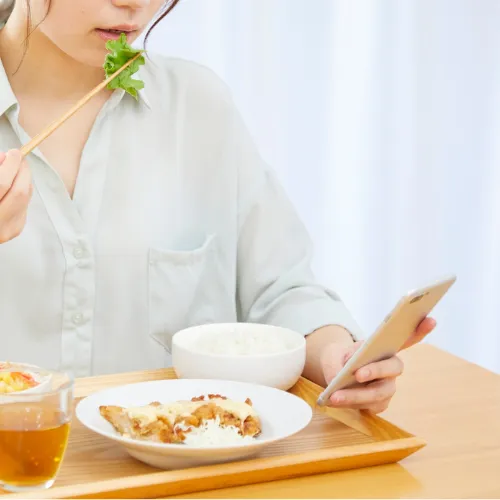 朝、食卓でスマホを見る女性